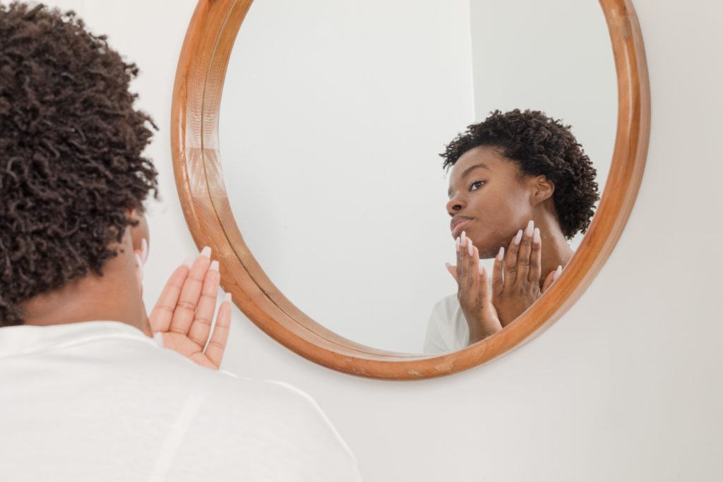 a woman in front of a mirror applying beauty tips on to her face 